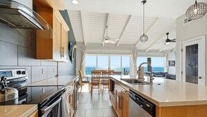 A modern kitchen with a large island, a built-in oven, and a dishwasher. - Oceanfront Condo | Balcony, Fire Pit | Shared Beach | Sleeps 6 (Oceanside)