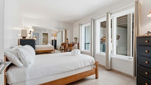 Ett modernt hotellrum med en stor säng, en byrå och utsikt genom ett fönster.