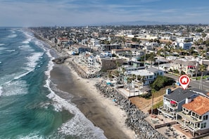 A coastal town with a beach, residential buildings, and a pier. - Oceanfront 3BR Condo | Balcony, Fire Pit | Shared Beach | Sleeps 6 (Oceanside)