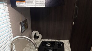 A kitchen with a sink, a stove, and a heart-shaped decoration. - Perfect  1-bedroom RV getaway located in Surfside Beach.  (Surfside Beach)