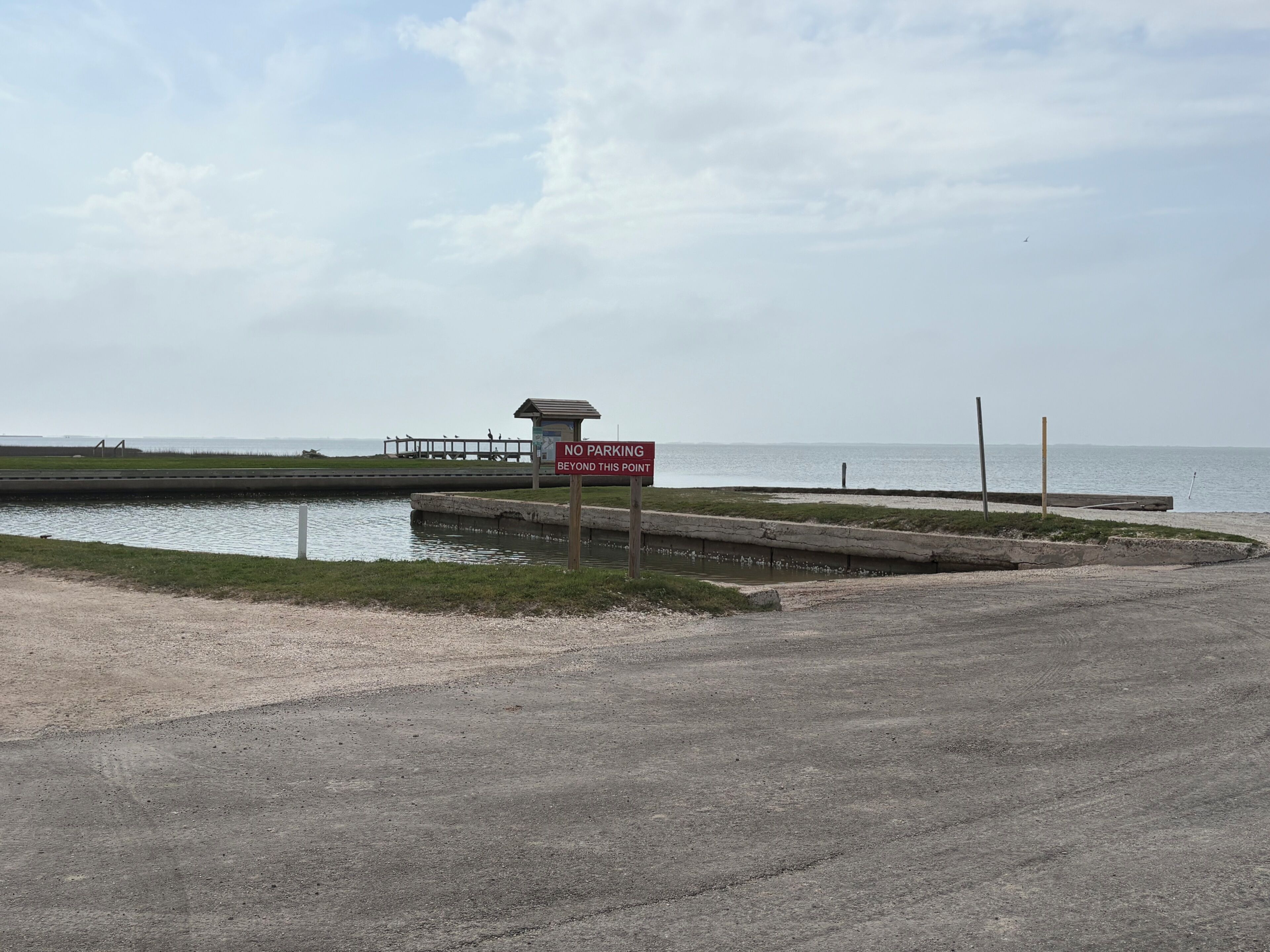 A no parking sign, a small structure, and a body of water.