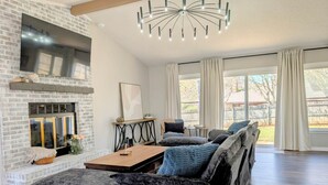Un salon avec une cheminée, un ensemble de canapés, une table basse et un lustre.