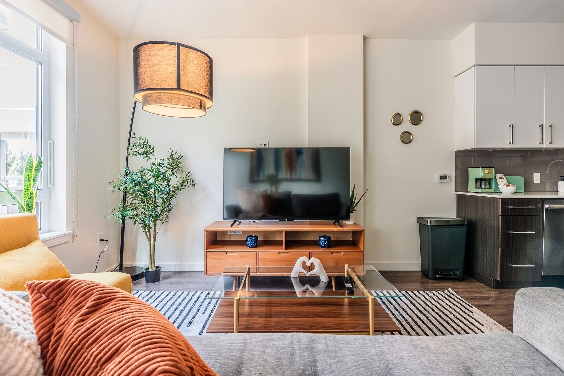 Una sala de estar moderna con un televisor de pantalla plana, un mueble de madera para equipo de entretenimiento y una cafetera.