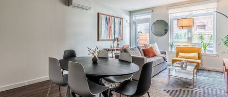 Una sala de estar moderna con comedor, un sofá, una mesa de centro y un ventanal con vistas.