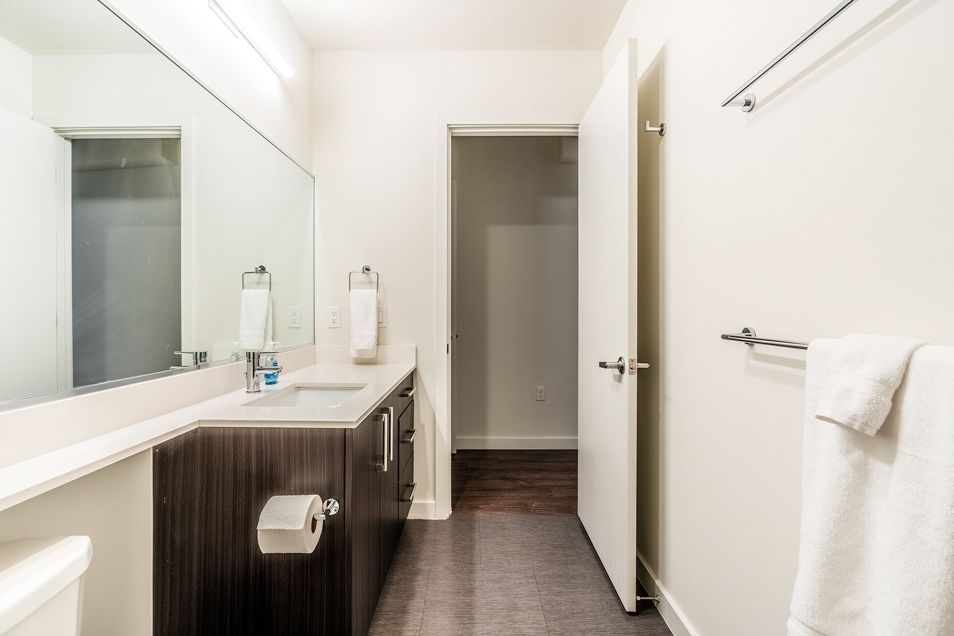 A bathroom with a mirror, sink, and towel rack.