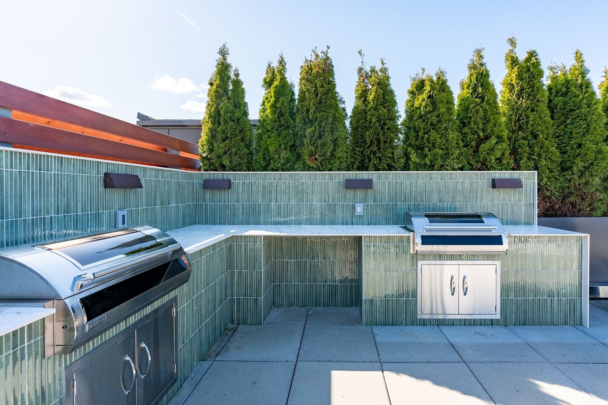 Een moderne buitenkeuken met een ingebouwde grill, een spoelbak en een kast.