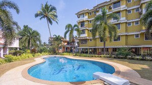 A swimming pool with a curved edge, surrounded by a concrete deck. - Elegant 2-Bedroom Duplex Apartment With 3 AC's In The Heart Of Benaulim (Benaulim)