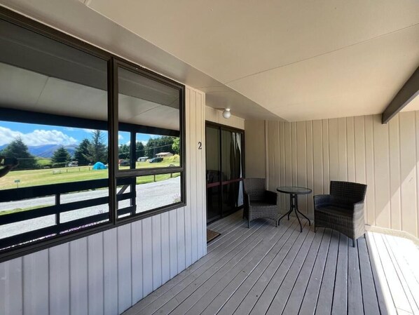 A balcony with a view of a green landscape and a mountain. There is a chair and a small table. - Mt Aspiring Suite - Near Roys Peak (Wānaka)