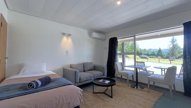 Habitación de hotel con cama, sofá, una mesita y vistas al exterior.