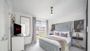 Un dormitorio moderno con una cama grande, televisión y vistas al exterior.