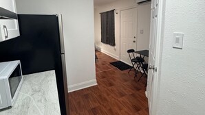 A compact kitchen with a microwave, refrigerator, and a dining area with chairs and a table. - Room, cozy and well-lit (Tampa)