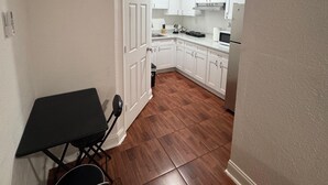 A narrow hallway leading to a kitchen with white cabinets and a dining area with a table and chairs. - Room, cozy and well-lit (Tampa)