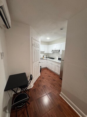A narrow hallway leading to a kitchen with white cabinets and a dining area with a table and chairs. - Room, cozy and well-lit (Tampa)
