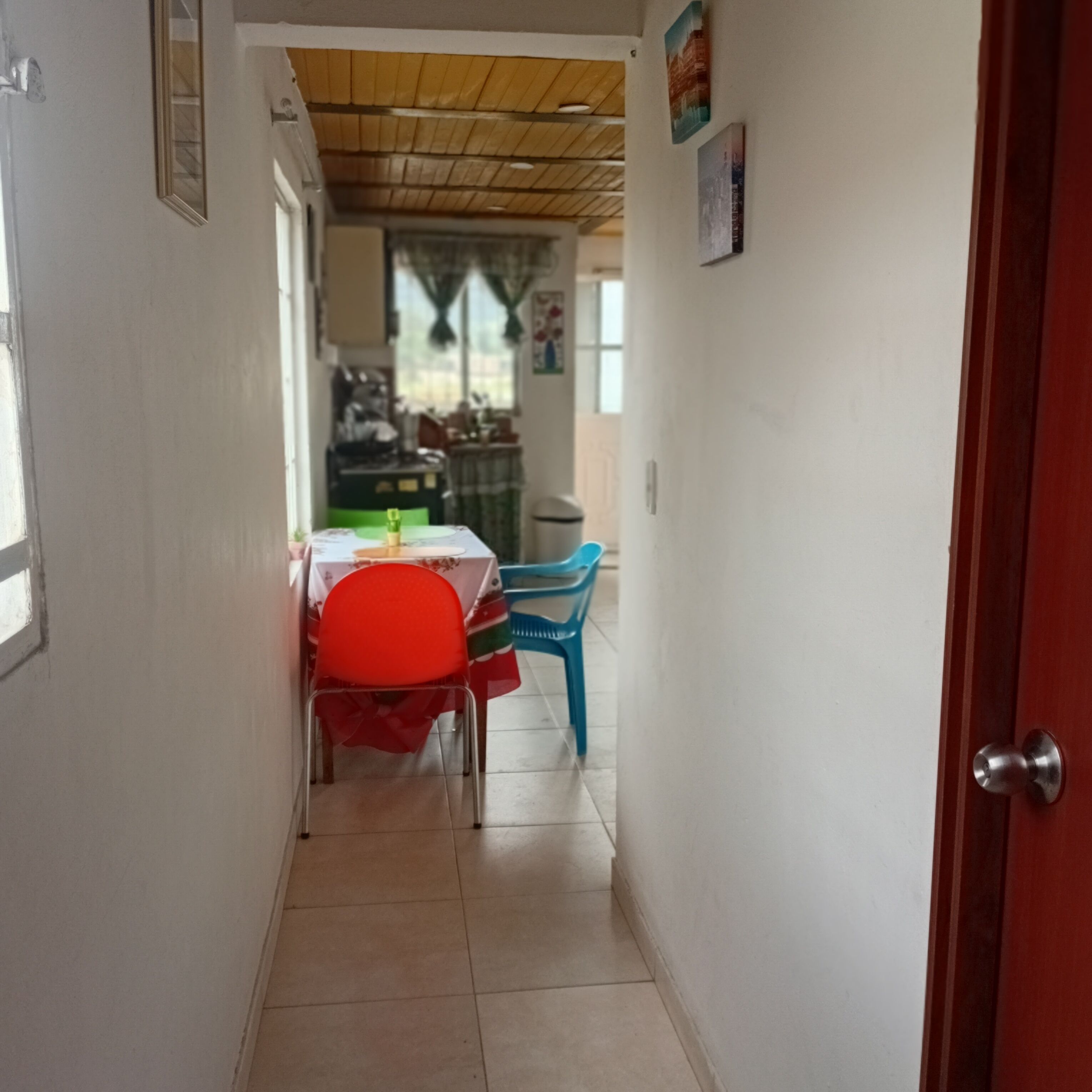 Un corridoio stretto che conduce a una sala da pranzo con tavolo e sedie.
