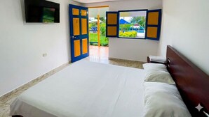 Ein Schlafzimmer mit Bett, einem an der Wand befestigten Fernseher und einer Tür zu einem Außenbereich.