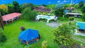 Ein großes Haus mit Schwimmbad, einem umzäunten Garten und einem Gebäude mit blauer Dachziegeldeckung.
