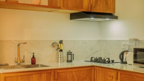 A kitchen with wooden cabinets, a stainless steel sink, a coffee maker, and a gas stove. - Premier Umalas Seminyak (Keroboken Kelod)