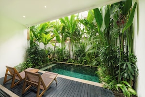 Ein Poolbereich mit Holzliegen, umgeben von üppiger tropischer Vegetation.