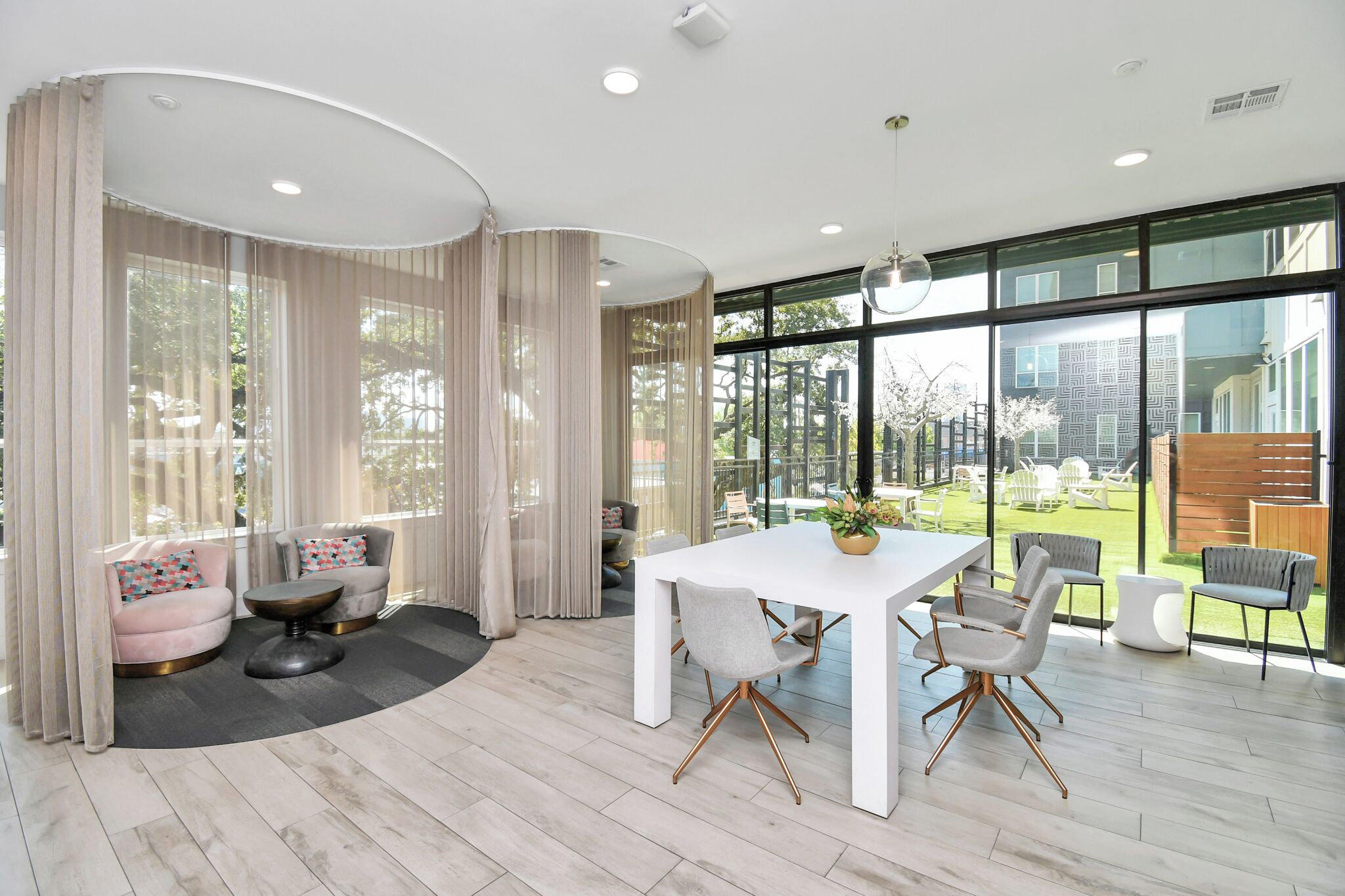 A modern interior with a dining area, large windows, and a view of the outdoors.