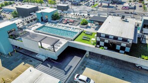 Ein Luftbild eines Hotels mit Dachpool, Außenbereich zum Sitzen und einem Parkplatz.