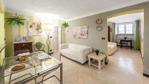 A living room with a white sofa, a glass dining table with plates, a small table with a lamp, and a plant. - Genova House Via Caffaro, Genova, Italy (Genova)