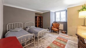 A bedroom with two metal beds, a red chair, a wooden cabinet, a lamp, and a window. - Genova House Via Caffaro, Genova, Italy (Genova)