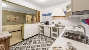 A compact kitchen with a patterned floor, a sink, and a dining area with a table and chairs. - Genova House Via Caffaro, Genova, Italy (Genova)