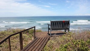A wooden bench with a heart decoration on a wooden platform overlooking the ocean.