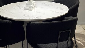 Un tavolo rotondo in marmo con una scultura di elefante bianco, circondato da quattro sedie nere.