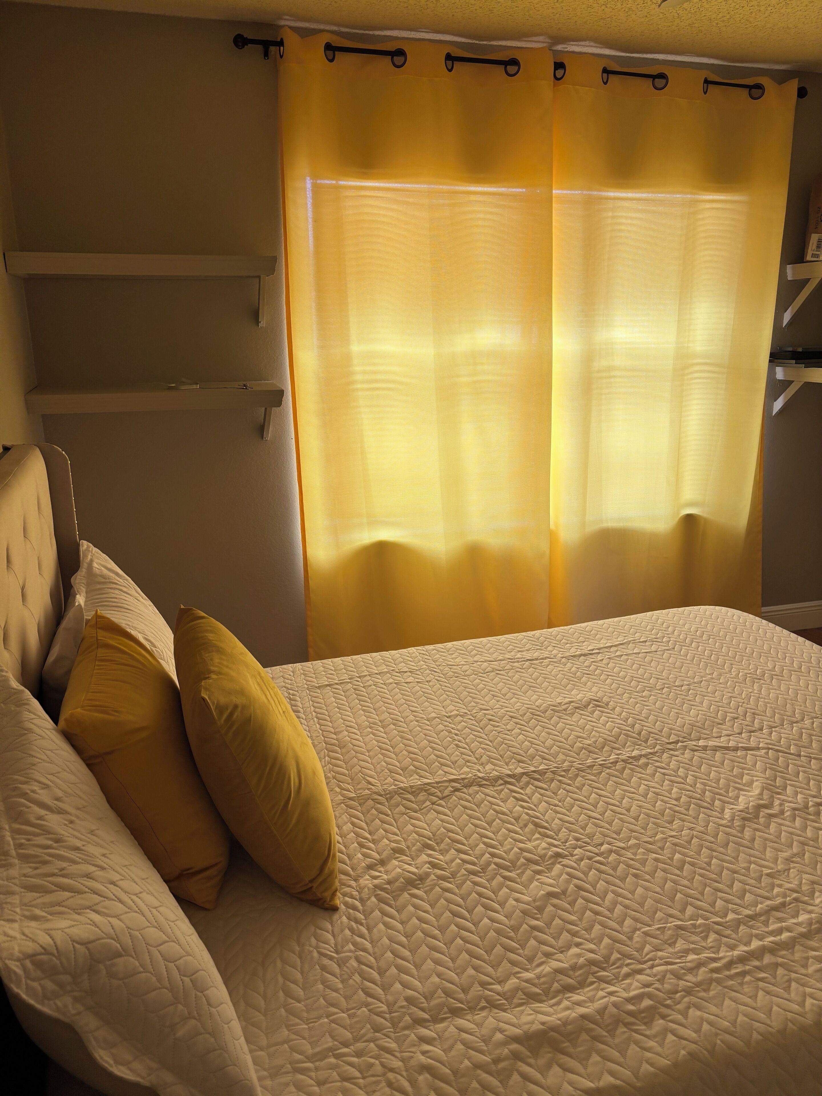 A bed with a quilted cover, a headboard, and two pillows.