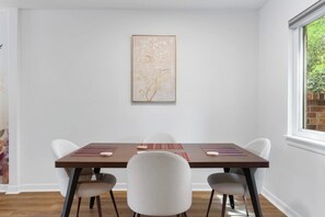 A dining area with a wooden table, four chairs, and a framed artwork on the wall. - 2BR 1.5BA Gorgeous Condo Near Hospitals - Shopping (Saint Andrews)