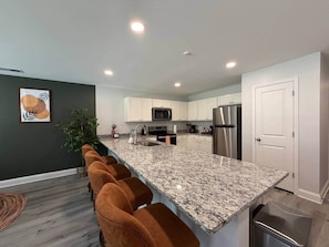 A modern kitchen with white cabinets, a granite countertop, and stainless steel appliances. - 3BR 2.5BA Fort Jackson | Fast WiFi + Parking (Dentsville)