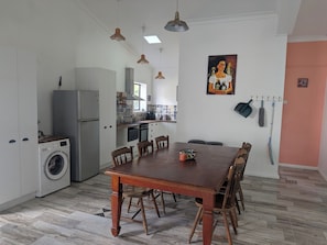 Une cuisine équipée d’un lave-linge, une table à manger avec des chaises et un tableau accroché au mur.