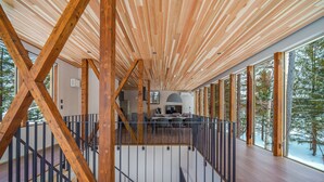 Un intérieur spacieux avec des poutres en bois, un balcon et de grandes fenêtres.