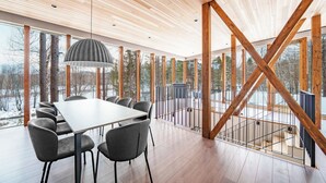 Un intérieur moderne avec un plafond en bois, de grandes fenêtres, une table à manger et des chaises.