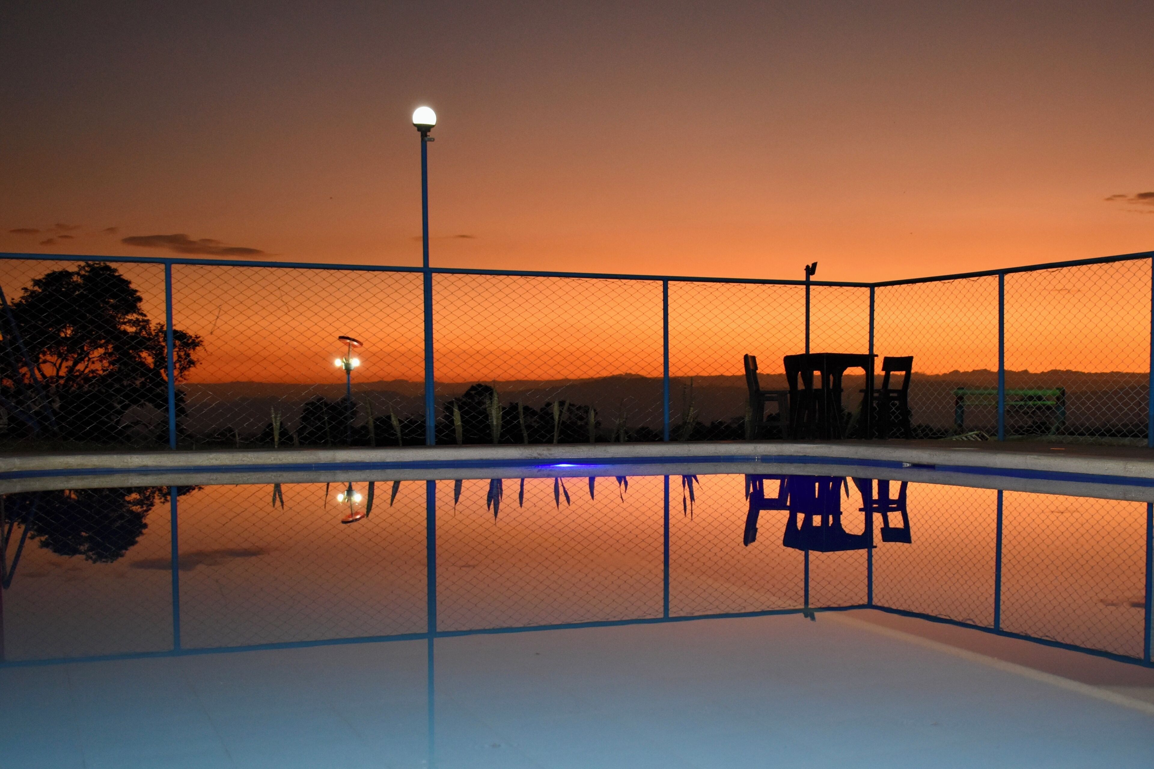 Ein Swimmingpool mit Zaun, einer Bank und einem Lampenpfahl.