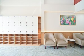 Un área de espera moderna con taquillas, un cuadro y sillones de cuero.