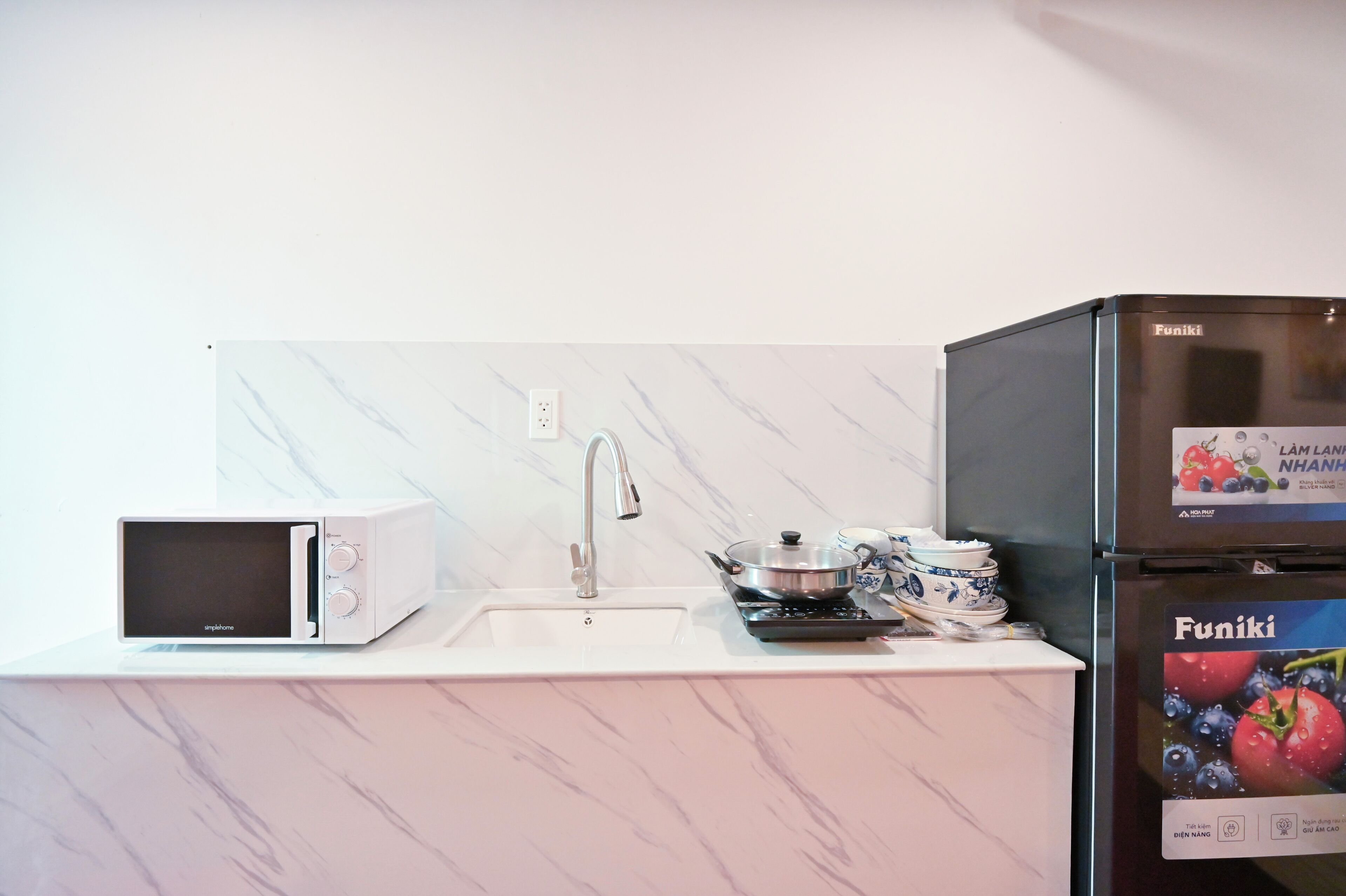 A kitchen with a white countertop, a microwave, a sink, a stove, and a refrigerator.