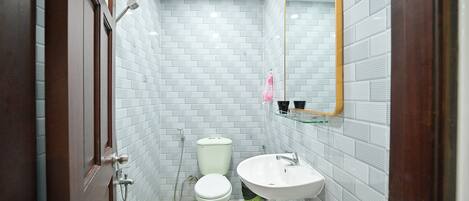 Un baño con paredes de azulejos blancos, un inodoro blanco, un lavabo y un espejo.