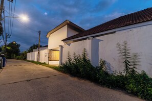 Asuinalueen katu, jossa on valkoinen talo, selvästi näkyvä autotalli ja kirkas taivas.