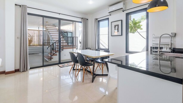 Una cocina moderna con comedor, una escalera y vistas al exterior.