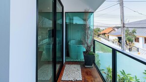 Un balcón moderno con puerta de vidrio, una planta en maceta y una pequeña zona de estar.