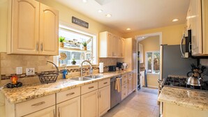 A kitchen with light-colored cabinets, a granite countertop, a stove, and a sink. - Block to Beach Family Home w/ King Bed, Jacuzzi & BBQ (San Diego)
