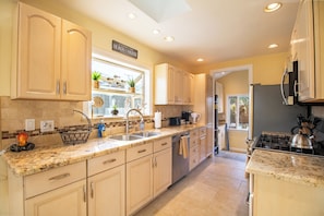 A kitchen with light-colored cabinets, a granite countertop, a stove, and a sink. - Block to Beach Family Home w/ King Bed, Jacuzzi & BBQ (San Diego)