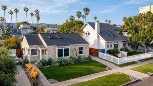 A residential house with a well-maintained lawn, a white picket fence, and a driveway. - Block to Beach Family Home w/ King Bed, Jacuzzi & BBQ (San Diego)