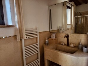 Ein Badezimmer mit Waschbecken, Spiegel, Handtuchhalter und einer Holzkiste mit einer Flasche.