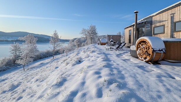 A snow-covered landscape with a wooden cabin and outdoor seating area.