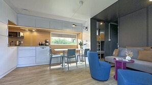 A modern kitchen with a dining area, a sofa, and a small table with a vase.