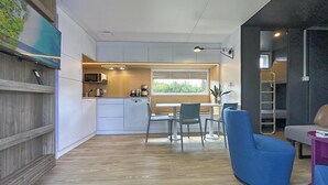 A modern kitchen with white cabinets, a dining area with a table and chairs, and a blue armchair.