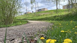 A gravel path leading to modern buildings on a grassy hill.